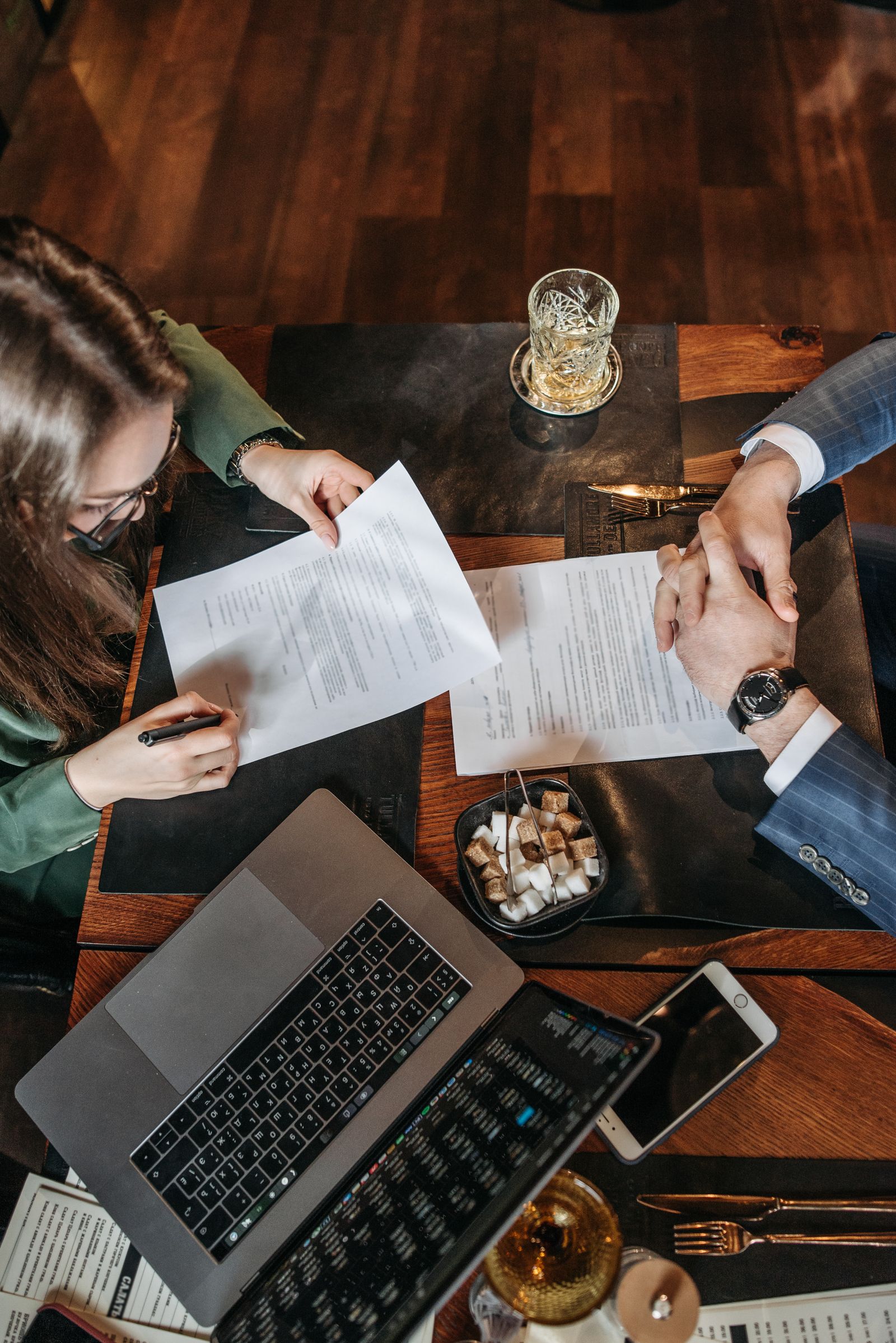 Professional reviewing and signing paperwork beside a laptop